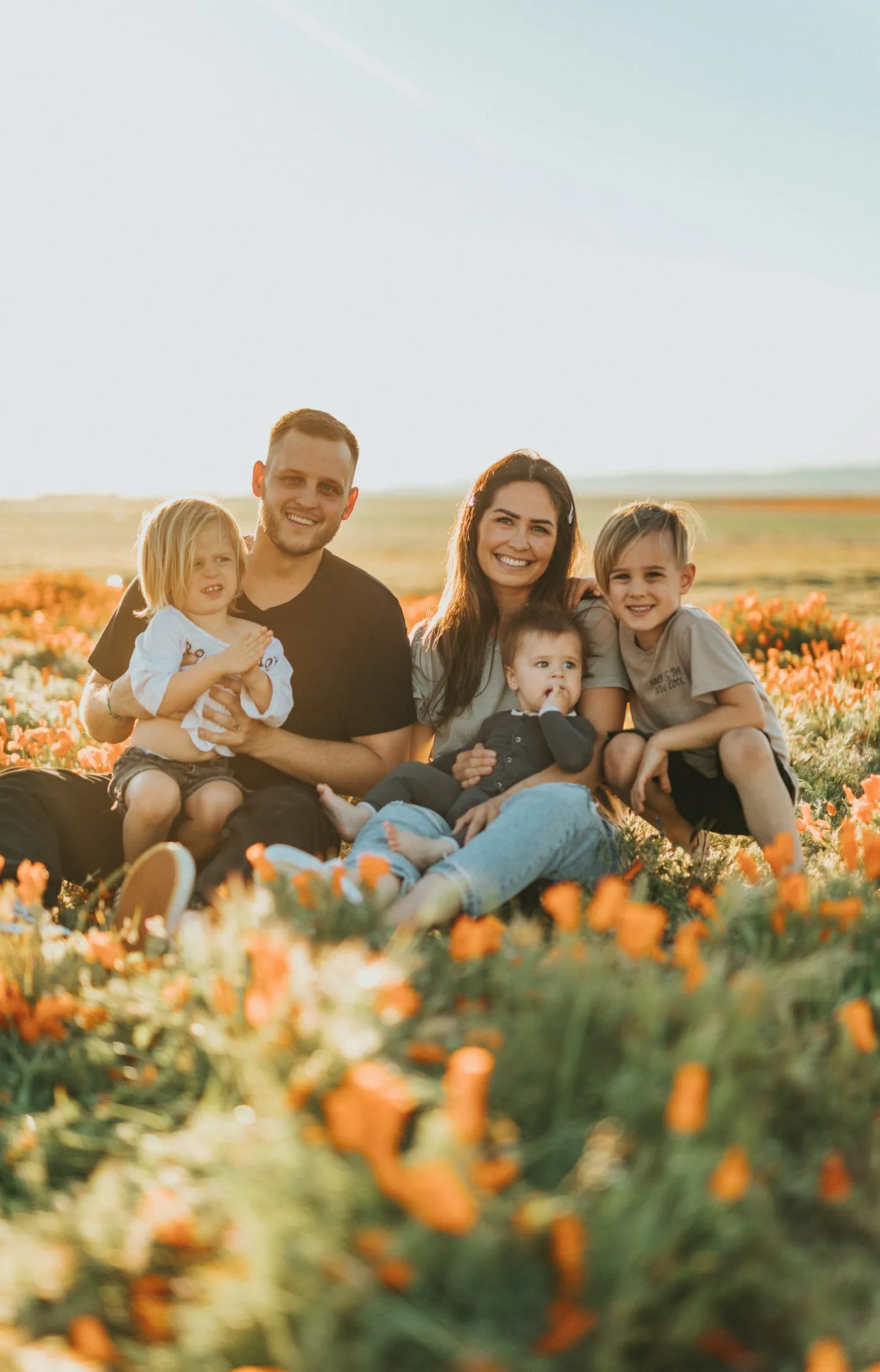 Casal com quatro filhos sentado num campo florido