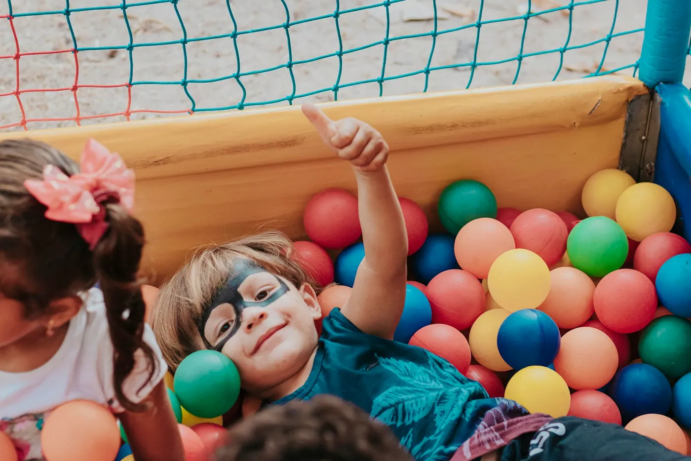 Criança deitada numa piscina de bolinhas coloridas