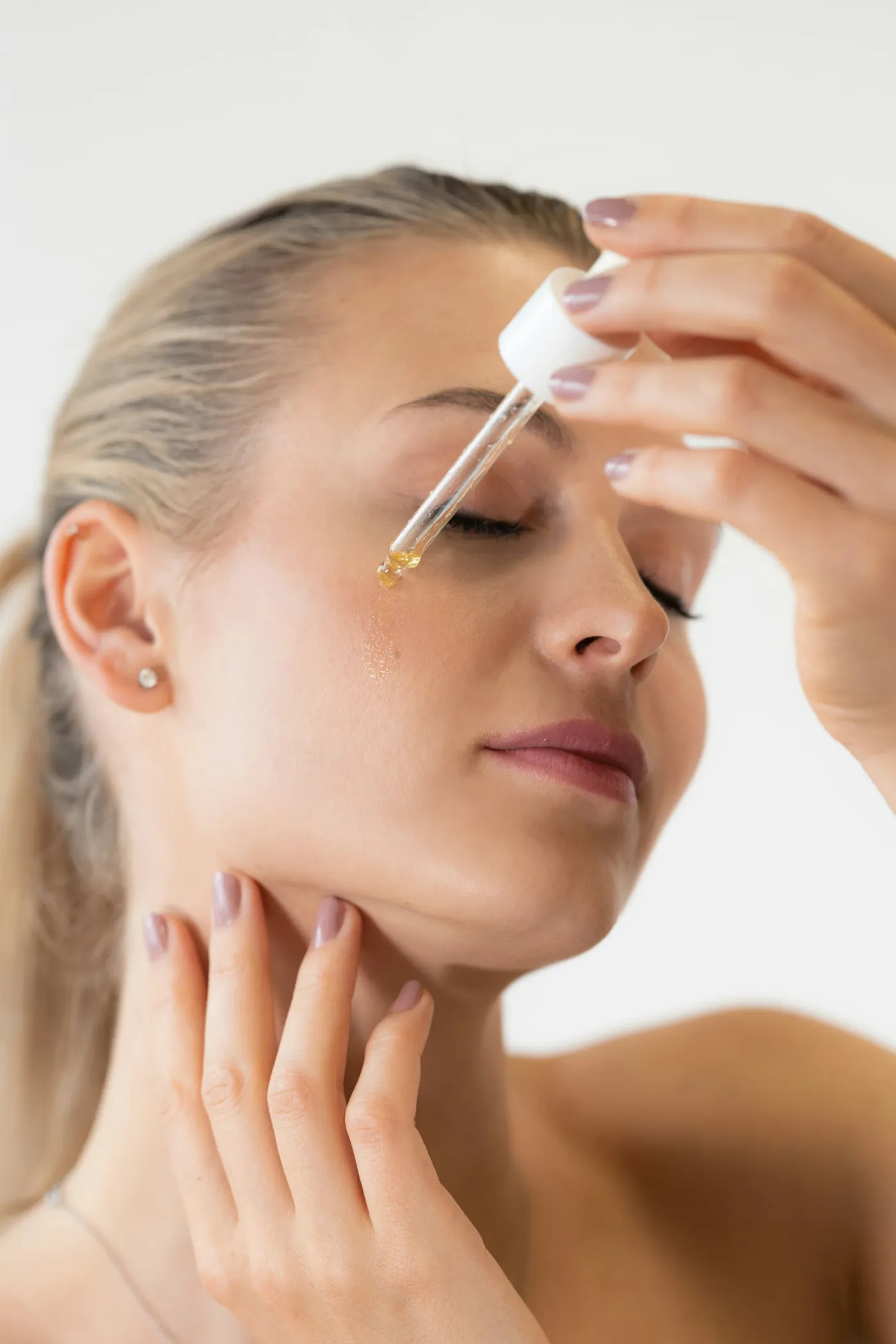 Mulher aplicando gota de sérum com conta-gotas no rosto
