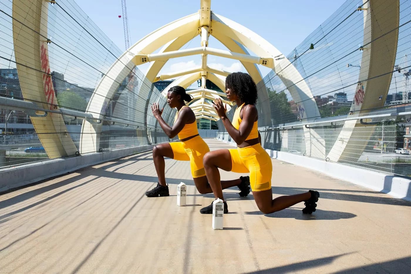 Duas mulheres em exercício de afundo numa passarela