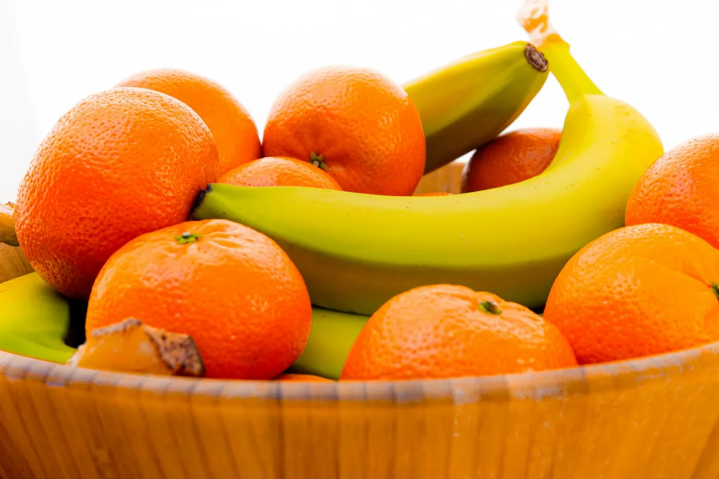 Fruteira de madeira cheia de tangerinas e laranjas, com duas bananas por cima